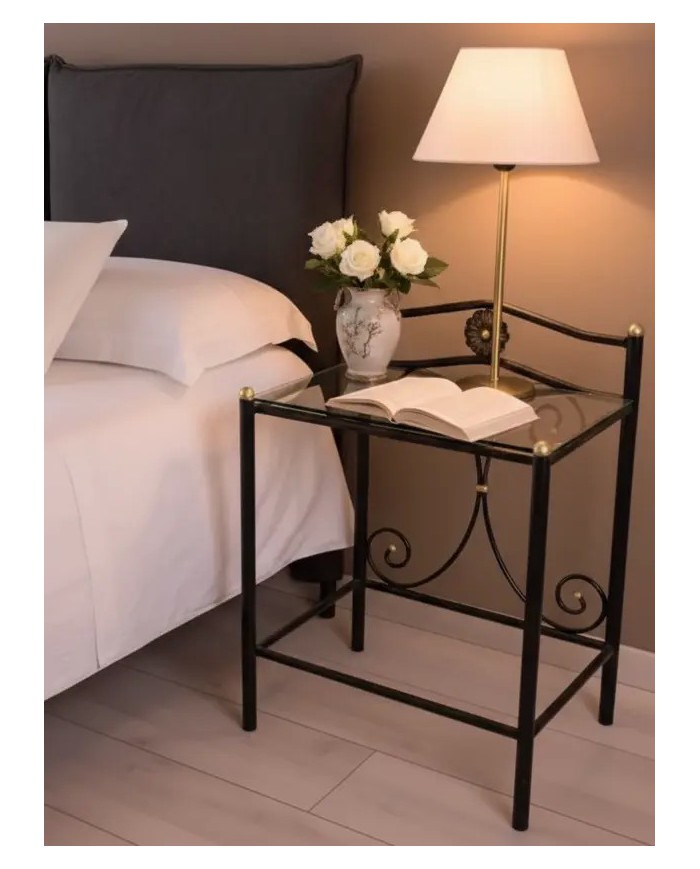 Comodino Laura in ferro battuto artigianale, finitura Nero oro, con doppio ripiano in vetro. Stile elegante e sobrio.